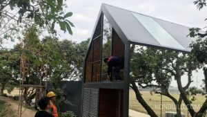 The "Loft Mirror" prefabricated building is almost finished with construction workers putting in the final components.