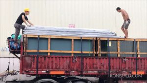 A modular resort building come packed from mainland china and is shipped word worldwide. Two men load good for Malaysia.